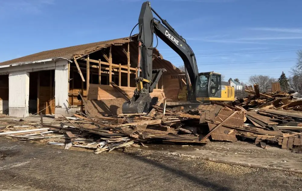 Excavator taking down an old timber-framed outbuilding