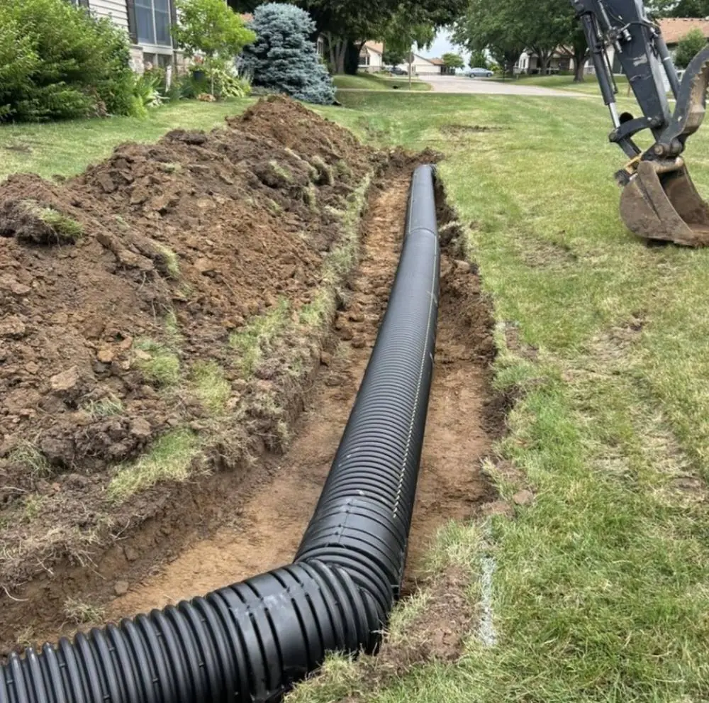 Large corrugated drainage pipe laid into an open trench across a lawn