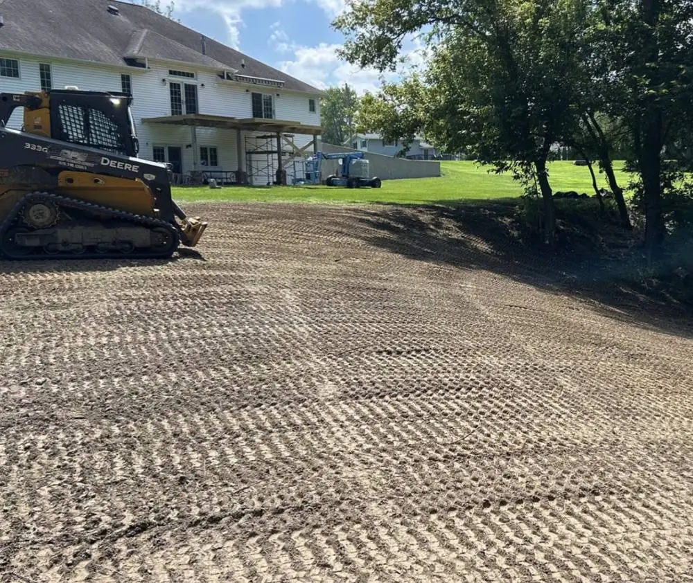 Freshly cut and tracked grade beside a house, ready for finishing