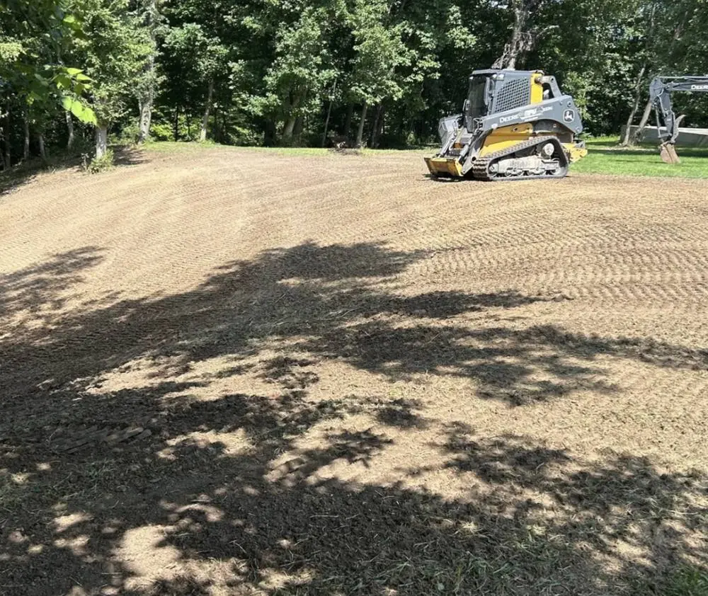 Skid steer shaping a graded slope down to a finished contour